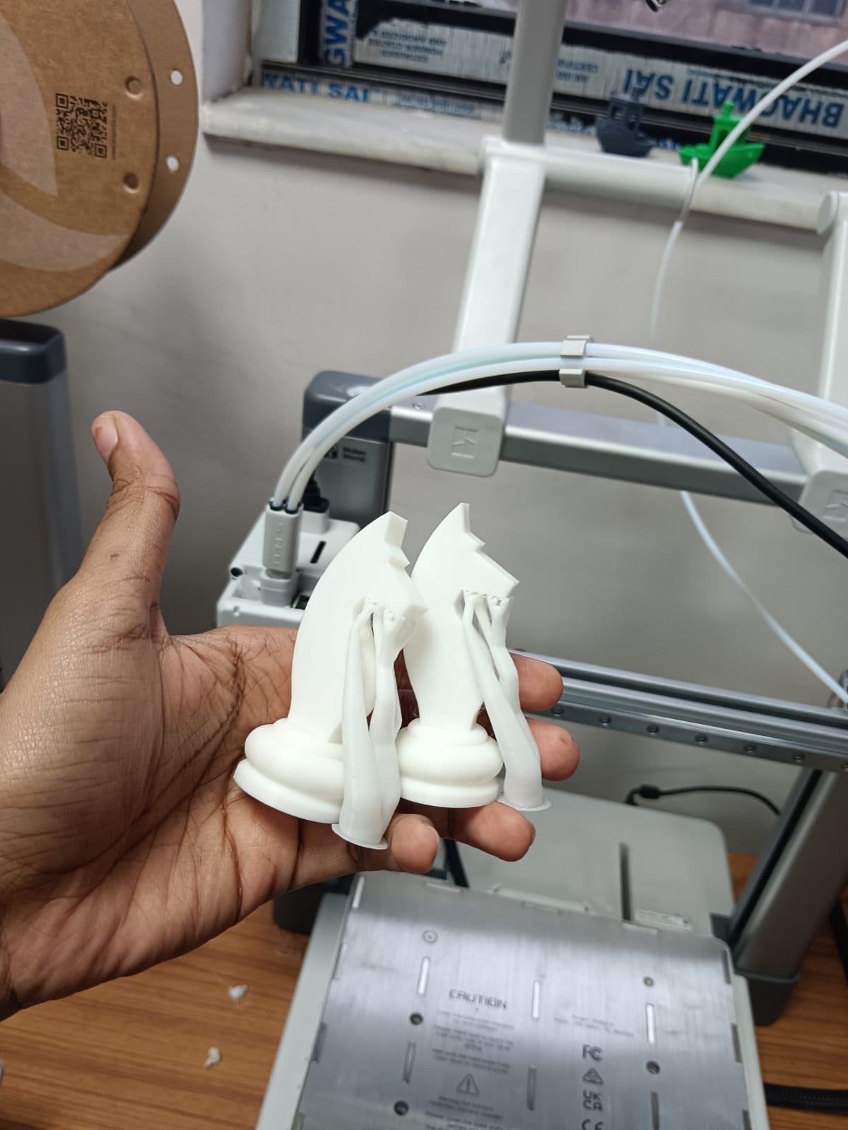 The finished high-resolution knights held in a hand in front of the printer