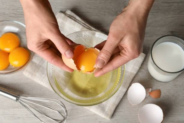 Hands cracking an egg over a bowl
