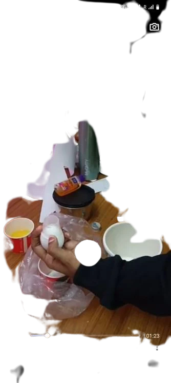 A hand holding the capped egg above a red cup