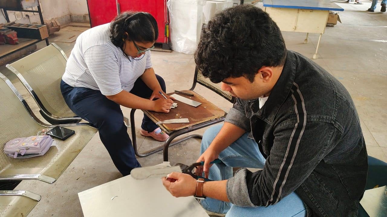 Two people marking and working on sheet material while seated