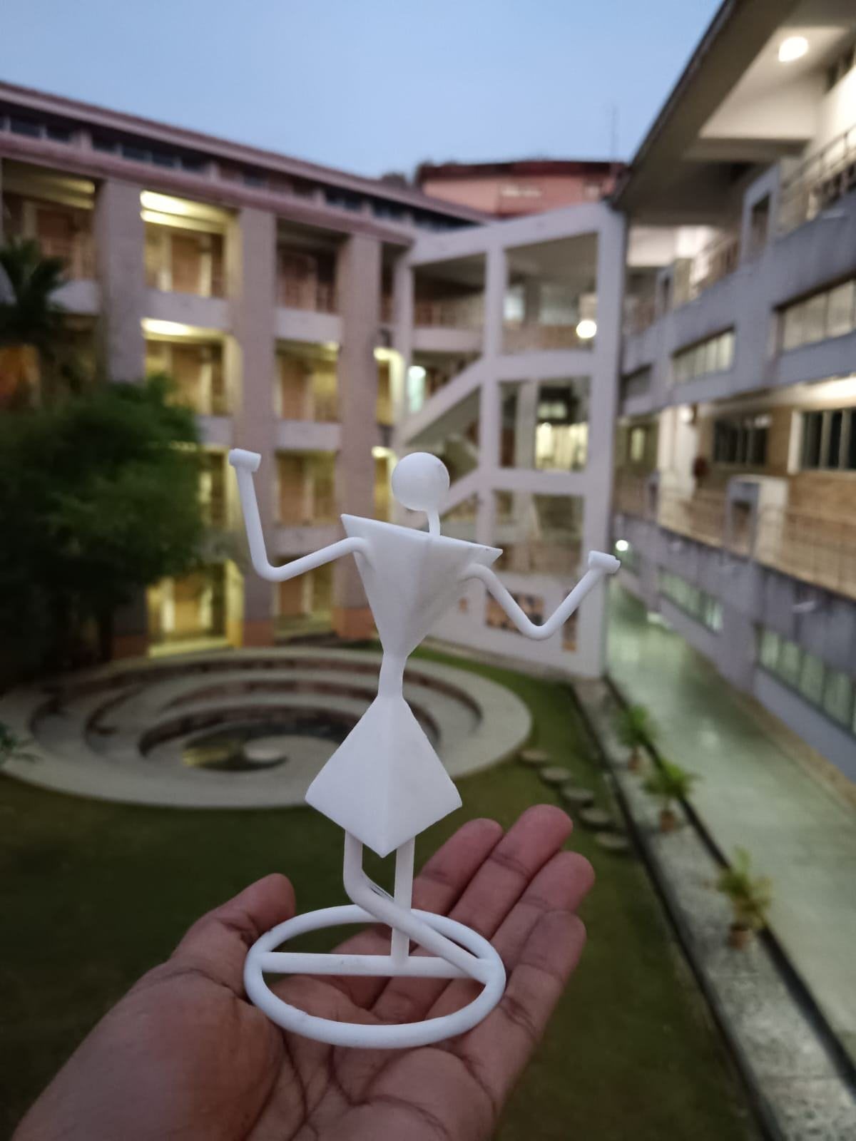The finished key holder held in a hand in front of a building at dusk